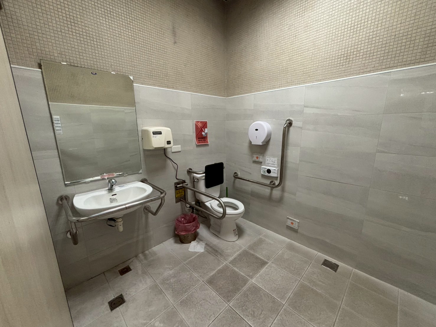 無障礙廁所內部為坐式馬桶，附有洗手台，馬桶及洗手台皆有加裝扶手